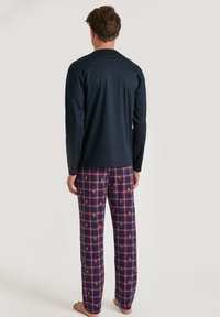 Heren loungewear set bestaande uit een lange mouw navy top en geruite pyjamabroek met rode, blauwe en gouden accenten. Zachte stof, relaxte pasvorm.