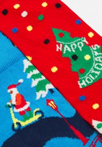 Knit holiday sweater fabric, split design: red with green tree and "Happy Holidays" text; blue with Santa on a scooter and snow-covered trees.