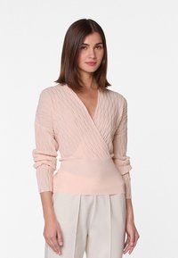 Langärmlige, hellrosa Wickeljacke mit strukturiertem Rippmuster und tailliertem Schnitt. Weicher Stoff mit tiefem V-Ausschnitt.