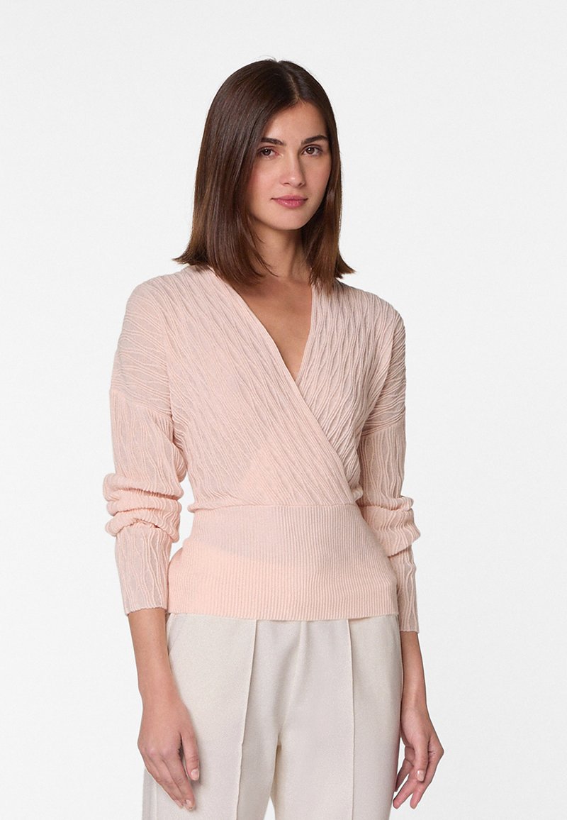 Langärmlige, hellrosa Wickeljacke mit strukturiertem Rippmuster und tailliertem Schnitt. Weicher Stoff mit tiefem V-Ausschnitt.