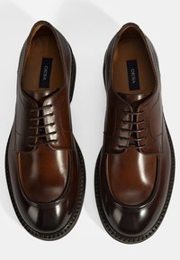 Bruine leren geklede schoenen met een gladde afwerking, ronde neus en vetersluiting. Inclusief decoratieve stiksels langs de randen.