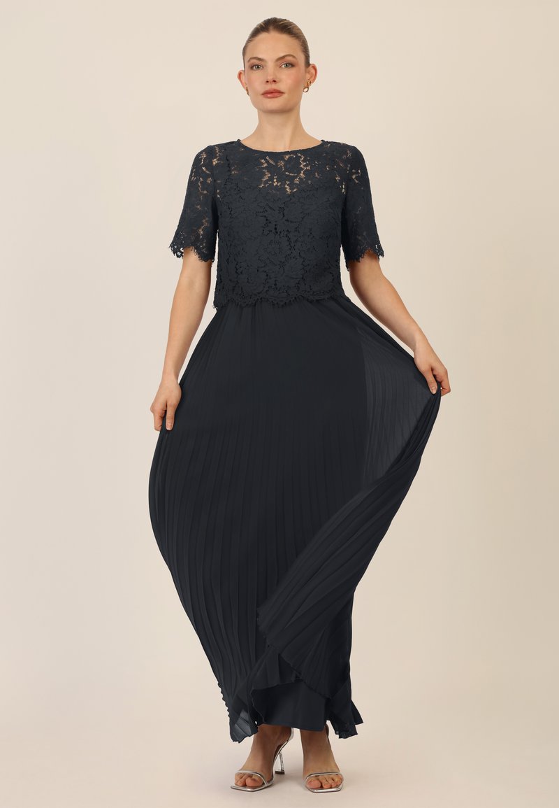 Zwart avondjurk met een kant bodice, korte mouwen, geplooide rok en ruches aan de onderrand. Glad materiaal met een vloeiende silhouet.