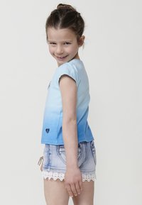 Modra ombre majica s kratkimi rokavi in emblemom srca, kombinirana z lahkimi jeans kratkimi hlačami z čipkastim robom in sprednjima žepoma.