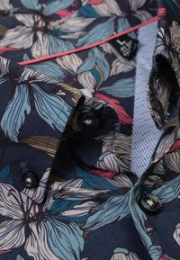 Korte mouwen shirt met donker bloemmotief, voorzien van blauwe en roze bladeren, zwarte knopen en een lichtblauwe gestructureerde binnenkraag.