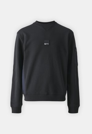 Felpa nera con collo rotondo, maniche lunghe e polsini a coste. Presenta una piccola etichetta del marchio sul petto e una tasca con cerniera sulla manica.