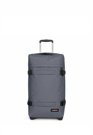 Sac à roulettes gris de forme rectangulaire, fabriqué en tissu durable. Il dispose d'une poignée télescopique, de boucles noires et d'un patch logo à l'avant.