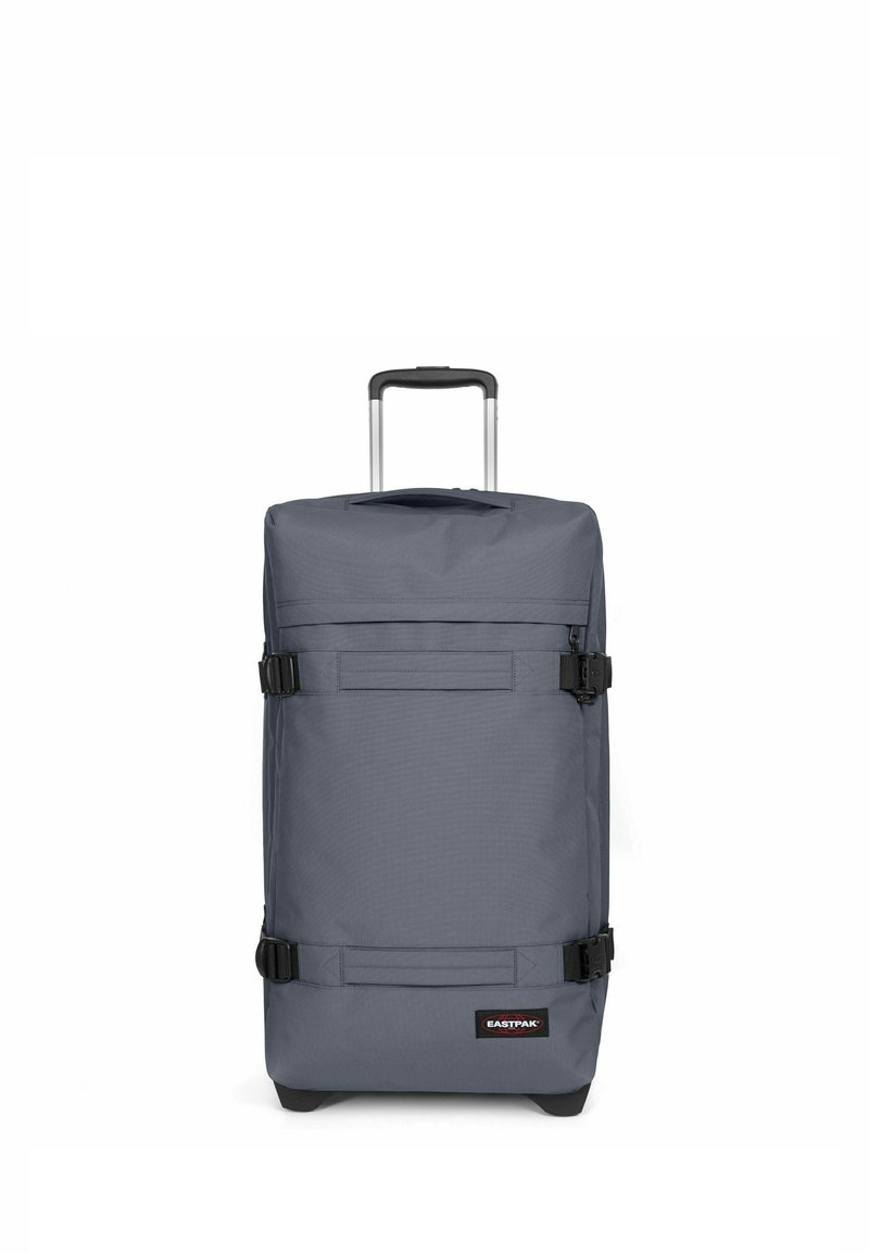 Sac à roulettes gris de forme rectangulaire, fabriqué en tissu durable. Il dispose d'une poignée télescopique, de boucles noires et d'un patch logo à l'avant.