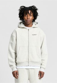Light gray zip-up hoodie made of soft fabric, featuring a kangaroo pocket and ribbed cuffs. Includes logo text on the left chest.