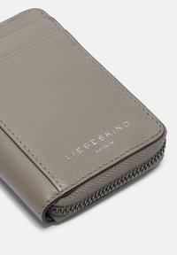 Billetera de cuero gris con un acabado texturizado, que cuenta con ranuras para tarjetas, un cierre de cremallera y nombre de marca grabado.
