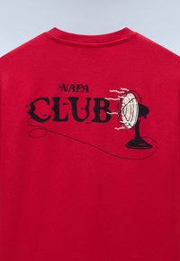 Dos d'un t-shirt rouge avec un graphisme en noir et blanc d'un ventilateur de table soufflant, et un texte indiquant "NAPA CLUB" au-dessus et à travers le ventilateur.