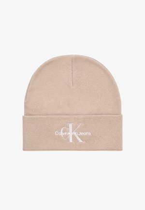 Berretto beige in maglia con risvolto. Presenta un logo "CK" ricamato bianco e la scritta "Calvin Klein Jeans", realizzato in tessuto morbido e strutturato.