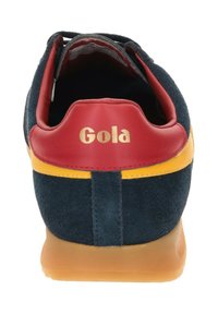 Marineblaue Wildledersneaker mit roten Lederakzenten, gelbem Besatz und einer Gummisohle. Mit "Gola" in Gold auf der Ferse.
