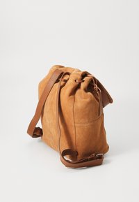 Sac seau en daim marron avec fermeture à cordon, base plate et bandoulière en cuir marron pour un réglage de la longueur de port.