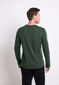 Zielona bawełniana koszula z długim rękawem, okrągłym dekoltem i gładką teksturą, zaprezentowana z tyłu, o dopasowanym kroju.