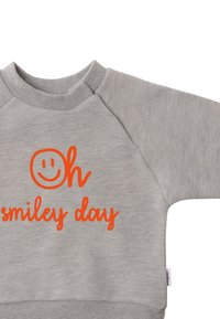 Light gray sweatshirt with a round neckline and raglan sleeves, featuring orange text that reads “Oh smiley day” above a smiley face graphic.