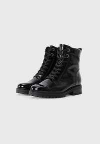 Bottines en cuir verni noir avec un bout arrondi, un laçage à l'avant, des œillets dorés et une semelle texturée épaisse.