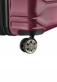 Valigia rigida di colore bordeaux intenso con finitura testurizzata, dotata di un bordo nero e di una ruota multiforo argento per una facile mobilità.