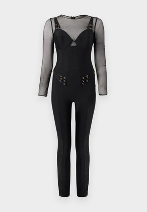 Črno oprijeto kombinezon z dolgimi prozornimi rokavi, strukturiranim zgornjim delom v slogu bustierja ter detajli z zlato zaponko na naramnicah in bokih.