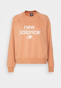 Felpa a maniche corte e colletto rotondo in tessuto color pesco, con audace logo bianco 'new balance' e orlo e polsini a coste.