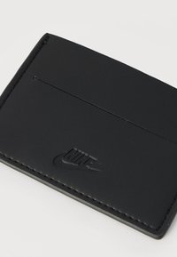 Μαύρο δερμάτινο θήκη καρτών με ανάγλυφο λογότυπο Nike, με κομψό σχεδιασμό, λεία υφή και μία θήκη για κάρτα στην κορυφή.