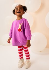 Paarse sweatshirt met een rendierontwerp op de borst, gecombineerd met rood-wit gestreepte legging en witte sneakers. Zachte stof en een losse pasvorm.