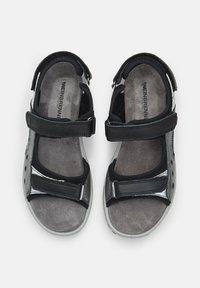 Mustad ja hallid sandaalid reguleeritavate Velcro rihmadega, polsterdatud sisetalla ja tekstuuriga kangast pealmise osaga. Omab toetavat disaini ja kummist tallasid.