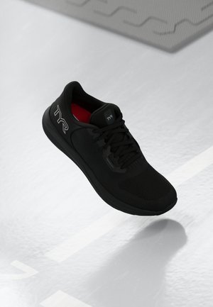 Chaussure de sport noire avec un dessus en maille texturée et un intérieur rouge contrastant. Comprend des lacets, une semelle rembourrée et un logo discret sur le côté.