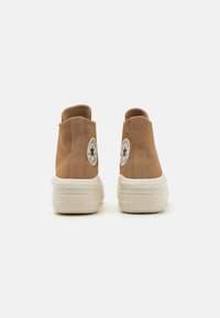 Bruine suède hoge sneakers met een witte rubberen zool en tong. Voorzien van iconische logo patch op de hiel en textuurpanelen aan de zijkant.