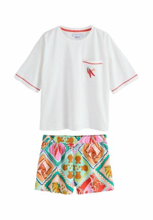 Weißes Kurzarmhemd mit kleiner Stickerei einer Chilischote auf der Tasche und rotem Besatz, kombiniert mit farbenfrohen gemusterten Shorts mit Muschel-Motiven.