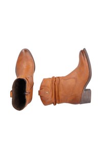 Botas de tobillo de cuero marrón con puntera ligeramente puntiaguda, diseño suelto y tacón apilado. Presentan un cierre lateral con cremallera y elementos decorativos.