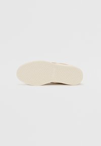 Sneaker marrone chiaro con suola in gomma di colore crema e texture. La suola presenta un motivo a diamante e un rettangolo con logo al centro.