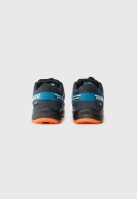 Black and navy running shoes with blue accents, orange sole, textured fabric, and a padded collar, featuring a prominent logo on the side.