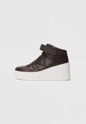 Wysoki brązowy skórzany sneaker z grubą białą podeszwą na platformie i rzepem wokół kostki, pokazany na jednolitym tle.
