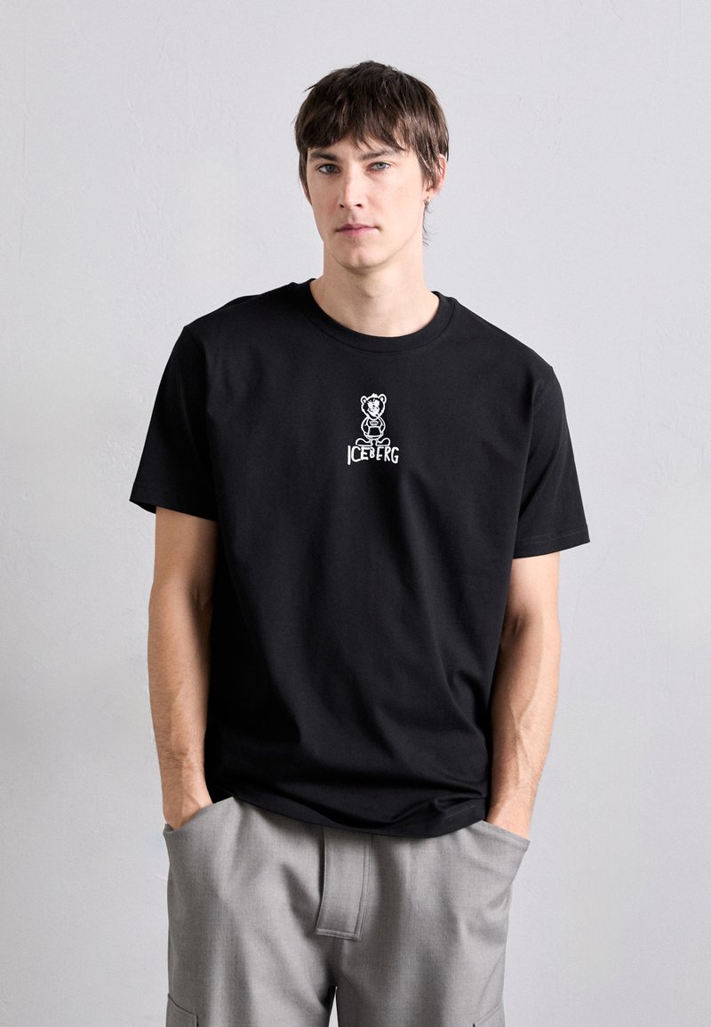 T-shirt en coton noir avec un graphique d'un ours et le mot "ICEBERG" en blanc, manches courtes, col rond et coupe décontractée.