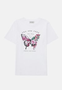 Bílý bavlněný tričko s růžovou grafikou motýla a květinovými detaily, s textem "JSI VOLNÝ, aby jsi mohl létat" a "ROZPÍNÁJ SVÁ KŘÍDLA".