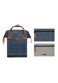 Marineblaue Canvas-Rucksack mit braunen Lederakzenten, ausgestattet mit einem Handgriff oben, einem Reißverschluss, Mini-Taschen in Marineblau und Grau mit Lederetiketten.