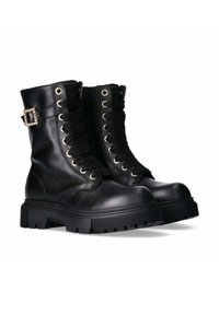 Stivali da combattimento in pelle nera con suola spessa, lacci neri strutturati, occhielli dorati e un accento decorativo a fibbia sul lato.