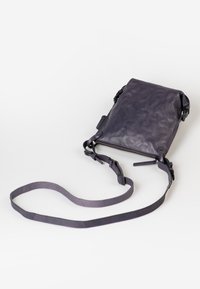 Borsa a tracolla in pelle viola con chiusura a zip, forma strutturata, tracolla regolabile e superficie liscia. Angoli rinforzati per una maggiore durata.