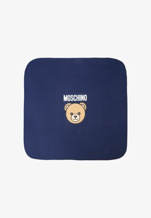 Plaid di colore blu navy con una grafica di un volto di orso color crema e il testo "Moschino" sopra. Texture morbida, angoli arrotondati e design minimalista.