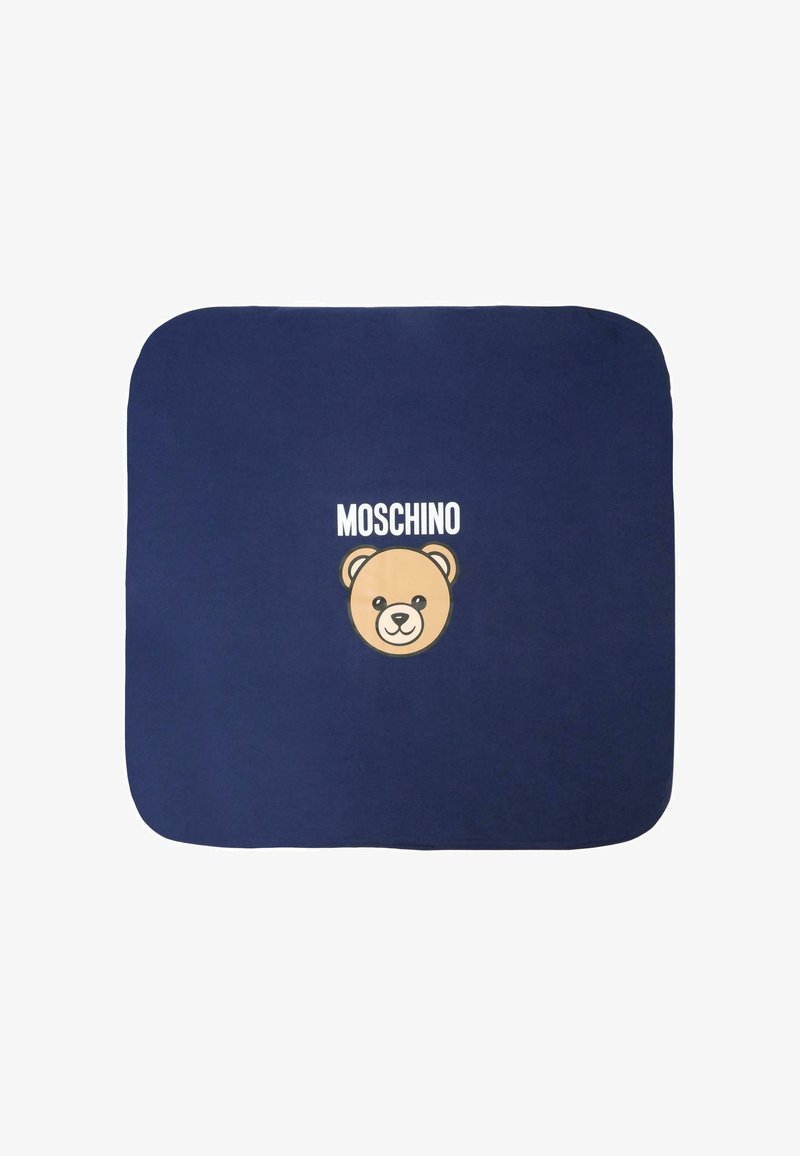 Couverture bleu marine avec un graphique en forme de visage d'ours crème et le texte "Moschino" en-dessus. Texture douce, coins arrondis et design minimaliste.