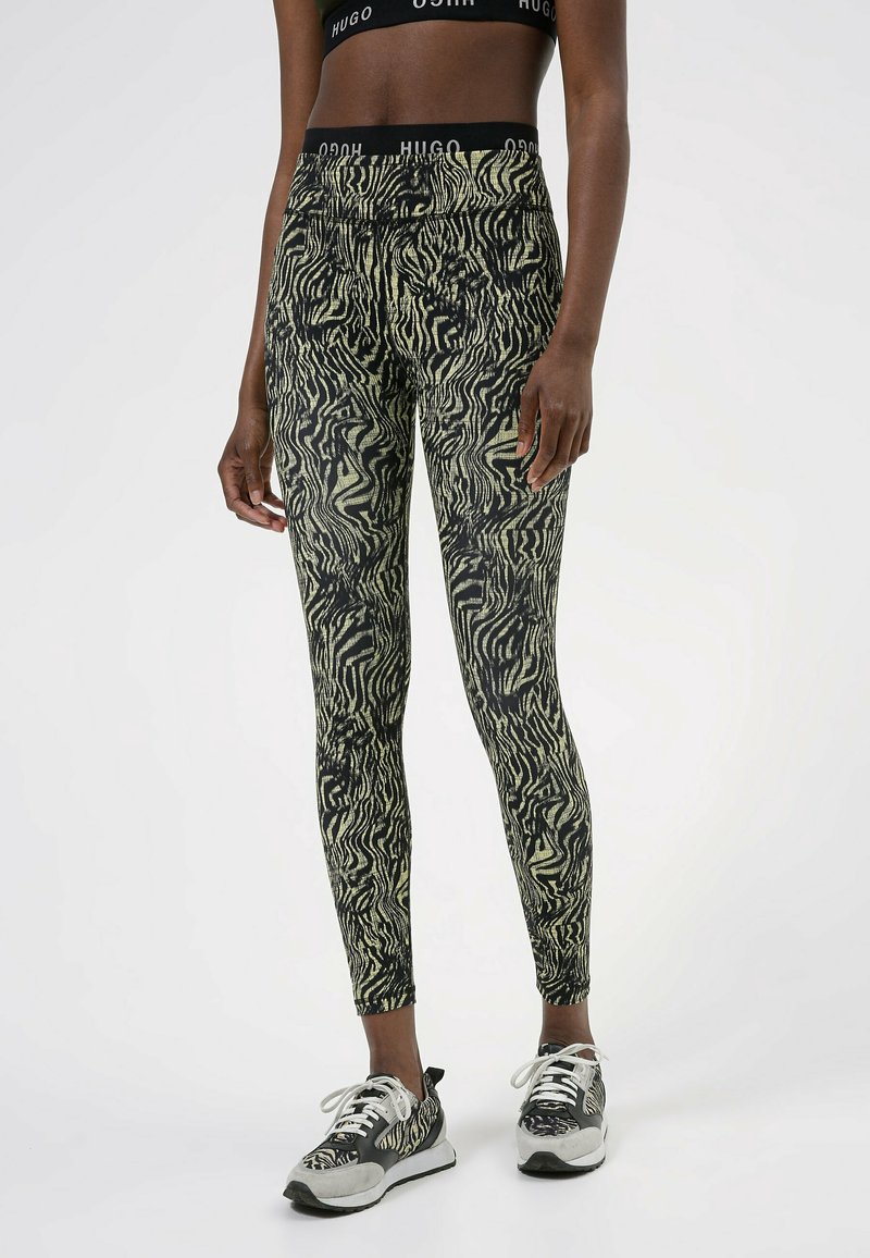 Leggings attillati in stampa zebra nera e gialla, realizzati in materiale elastico, con vita alta e una texture liscia.