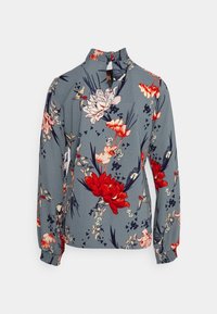 Blusa floreale in tessuto azzurro chiaro, con fiori rossi e rosa, maniche lunghe, colletto arricciato e polsini elastici. Dettaglio a oblò sul retro.