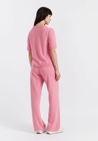 Top in maglia rosa con maniche corte e pantaloni abbinati dal taglio morbido. Tessuto morbido, dettagli a coste sui polsini e sull'orlo, design casual.