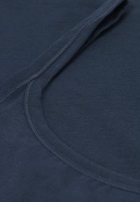 Close-up of a dark blue fabric with visible neat stitching along a curved seam, highlighting textile texture and construction details.