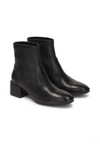 Botas de tobillo de cuero negro con punta afilada y tacón cuadrado. Acabado suave, lados elastizados y detalle de costura mínima.