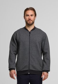 Grå zip-jakke med en tekstureret stof, ribbede manchetter og en sort krave. Har en lige pasform og en funktionel lynlås i fuld længde.