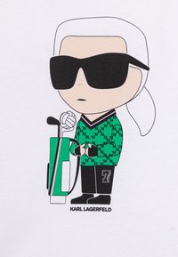 Personaggio dei cartoni animati con camicia bianca, occhiali da sole neri, maglione a scacchi verde, che tiene una borsa da golf colorata con il numero 7 sui pantaloni.