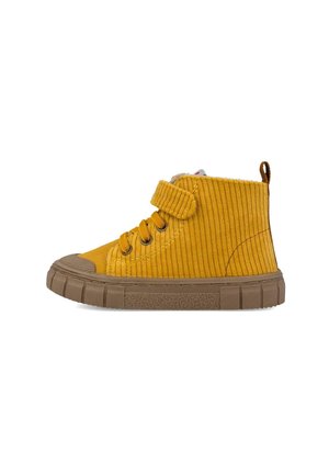 Zapatilla alta de pana amarilla con suela de goma marrón, cordones y una correa de velcro sobre fondo blanco.