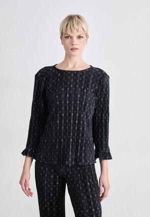Top nero a fantasia con maniche a tre quarti, scollo rotondo e bordi arricciati sulle maniche. Il tessuto presenta linee verticali con piccoli design circolari.