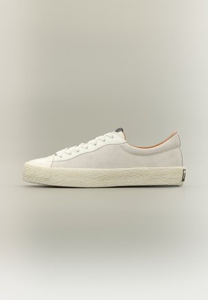 Niski biały sneaker z teksturowaną podeszwą, sznurowaniem z przodu i gładką cholewką, pokazany z boku na neutralnym tle.